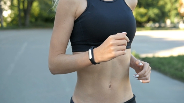 Beautiful Fit and Healthy Blonde Woman Road Running With Fitness Tracker