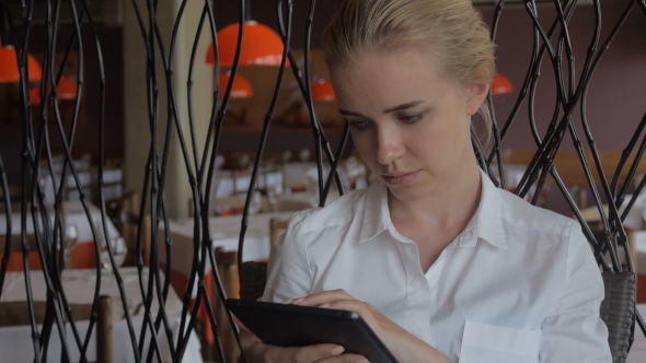 Young Beautiful Blonde Straight Hair Woman in the City Sitting at the Restaurant Using Tablet