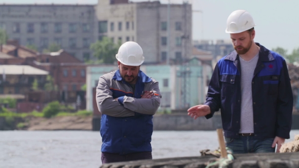 Two Workers Walking And Talking In Front Of The Cargo Ship