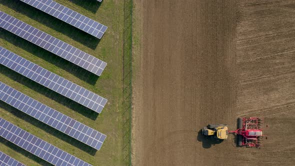 New and Old Farming as a Seed Drill Works Alongside a Solar Power Farm