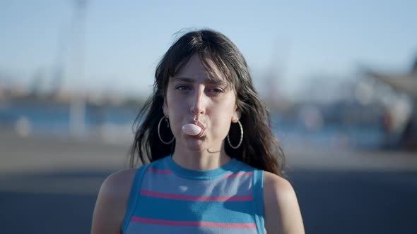 Close View of Happy Darkhaired Girl Trying to Blow Chewing Gum Bubble