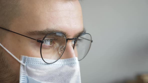 Close-up of a Man Doctor wearing Glasses and a Mask Looking Away and Talking to a Patient