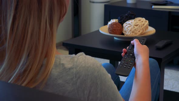 A Woman Switches Channels on a TV with Remote Control, Detail of Hand