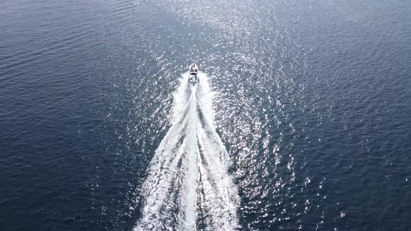 A speedboat rushes forward on the water of the blue sea. Boat in the ocean view from the drone