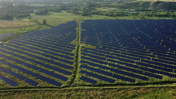 Aerial Top view on Solar Power Station in Green Field on Sunny day. Drone fly over Solar Farm