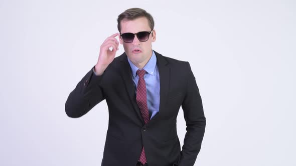 Young Handsome Businessman Removing Sunglasses and Looking Shocked