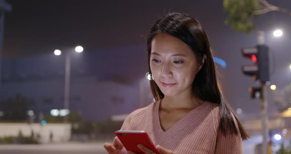 Woman use of smart phone in city at night