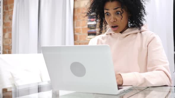 Shocked Wondering AfroAmerican Woman Working on Laptop Sitting at Home