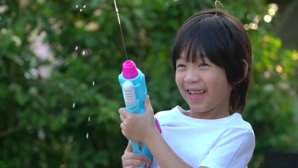 Cute Asian Child Playing With Water Gun In The Summer