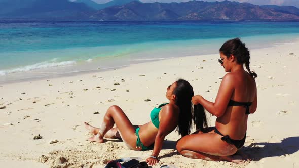 Girls happy together on paradise lagoon beach break by aqua blue lagoon with white sand background o