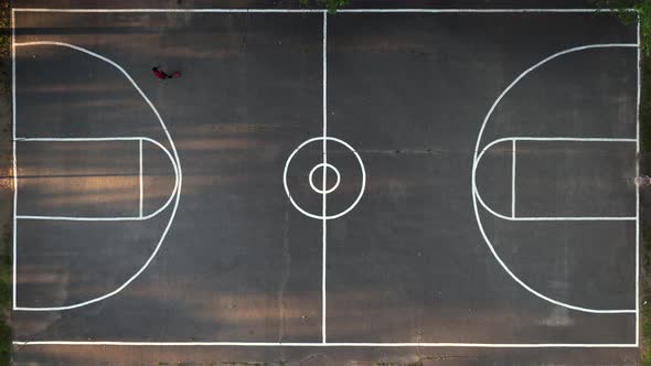 A top down view directly above a basketball court in a park on Long Island, NY. It is a sunny day an