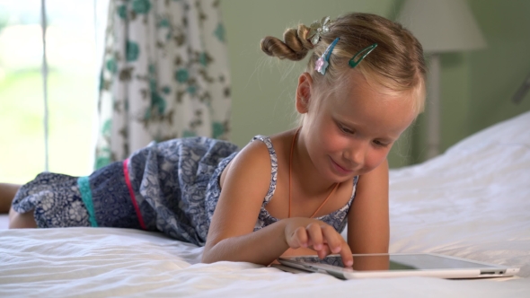 Little Cute Girl Plays a Game On The Tablet