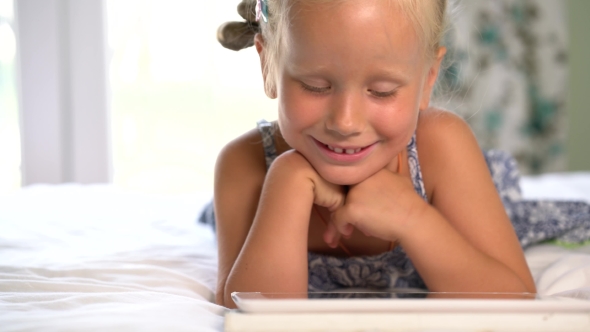 Little Cute Girl Plays a Game On The Tablet