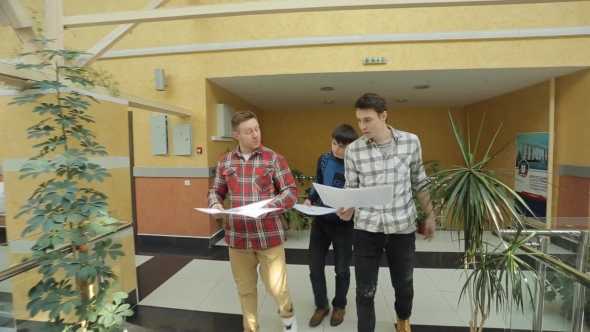 Three Student Walk With Blueprint Inside University Of Art.