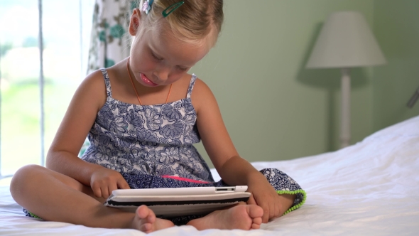 Little Cute Girl Plays a Game On The Tablet