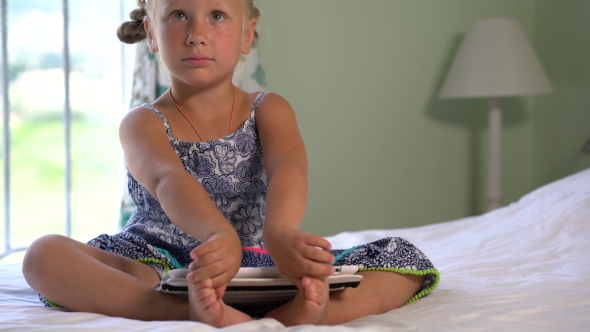 Little Cute Girl Plays a Game On The Tablet