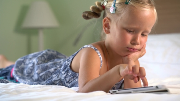 Little Cute Girl Plays a Game On The Tablet