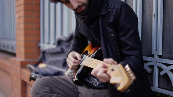 Guy Playing on the Giutar with a Pick on the Street