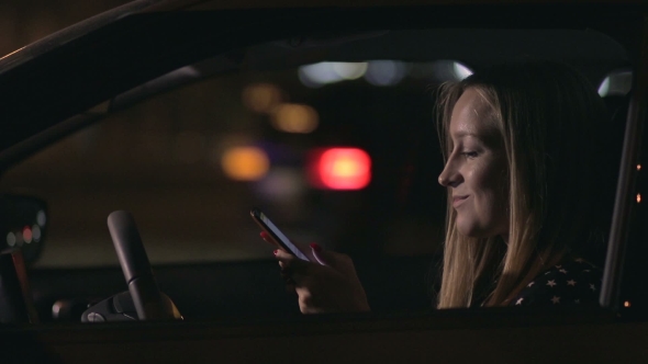 Charming Woman Texting Message On Cellphone In Car