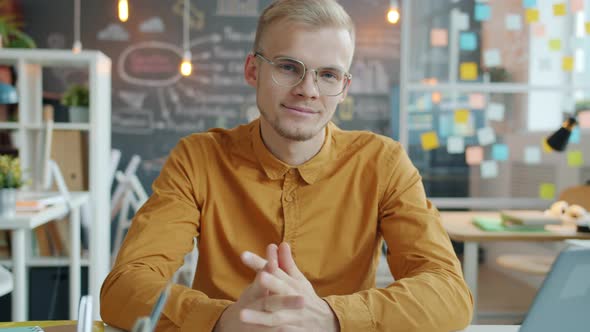 Portrait of Cheerful Businessperson Smiling Sitting at Desk in Creative Office Room