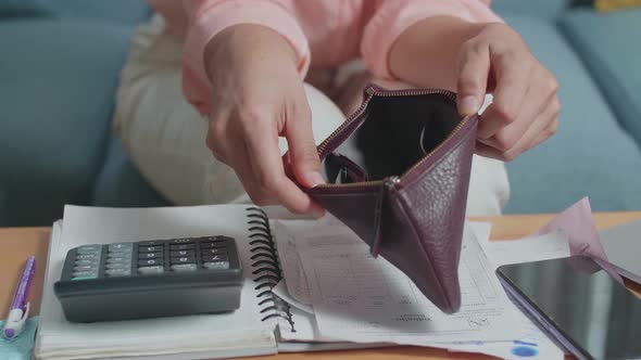 Close Up Of Woman's Hand Calculating Money By Calculator Before Opening The Purse To Check Money