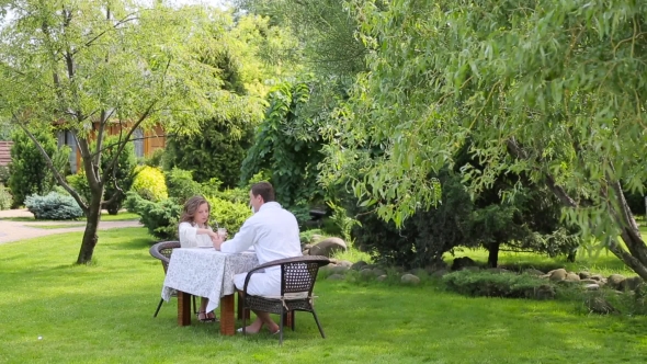Couple In The White Bathrobes Have Breakfast In The Garden
