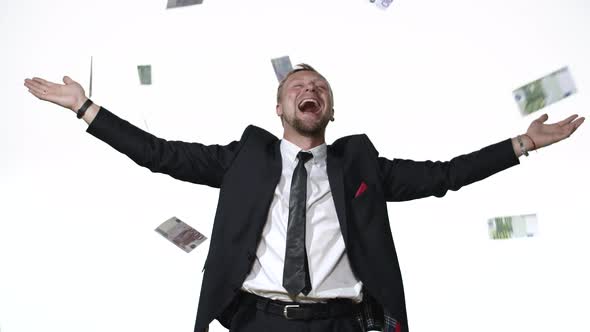 A Man in a Business Suit Exults in the Rain of Money in a White Studio