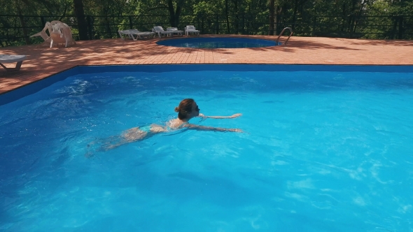 Blonde In Sunglasses Is Swimming In a Pool Outdoor And Going Out By Stairs