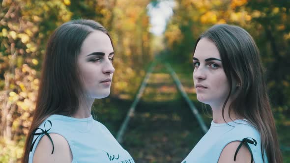 Twins Girls on Railroad Look at Camera in Green Nature Background