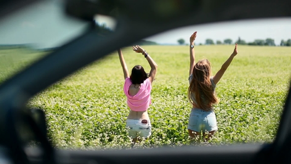 View Through Car Window Of Women Jumping In Field