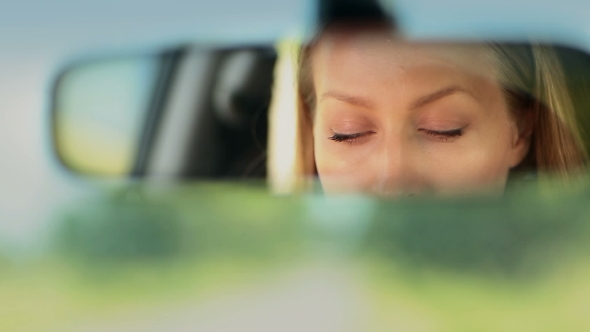 Reflection Of Woman's Blue Eyes In Rearview Mirror