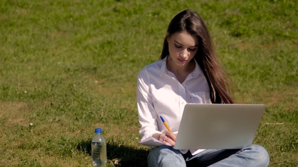 Cute Student Girl Working With Laptop And Papers In Park Of An University Campus