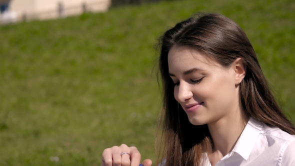 Beautiful Brunette With Long Hair In The Wind Drinking From a Bottle Of Water