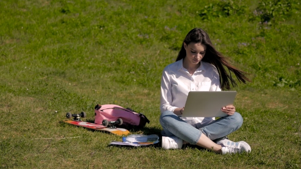 Young Pretty Hipster Student Girl Using Laptop In a Park, Net Surfing Outdoors