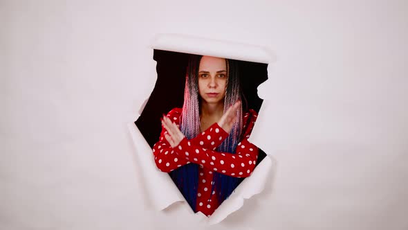 Young Woman Making Stop Gesture and Looking Out of Hole of White Background