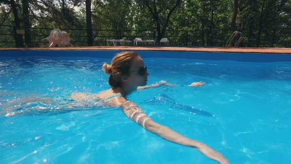 Blonde In Sunglasses Is Swimming In a Pool Outdoor And Going Out 