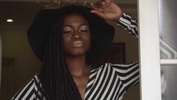 Of Elegant Sexy African American Female Model In Black Hat And Striped Dress Posing At The Luxury