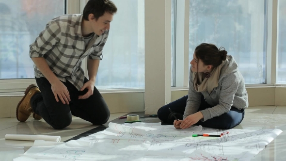 Two Persons Sit On Floor And Discuss Plan Of Building