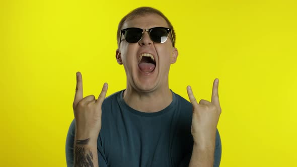 Man Posing in T-shirt. Crazy Guy Shouts, Celebrates, Wins, Shows Tongue, Makes Horns Symbol