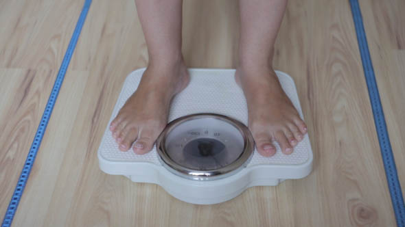 The Girl Checks for the Weight on the Scales of