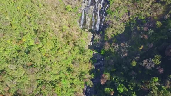 Flycam Moves Along Gorge with River Cascade in Thick Jungle