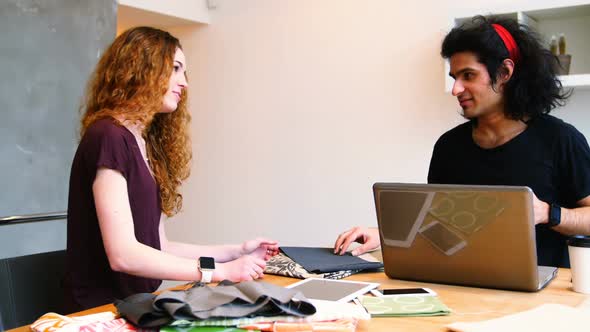 Executives using laptop while examining fabric