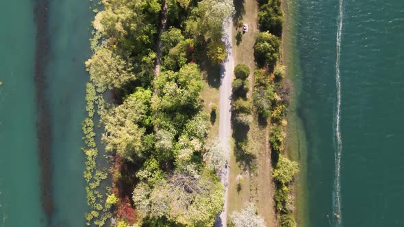 Aerial view of a cyclist driving on a dirt path surrounded by water. Cyclist enjoying a fun drive al