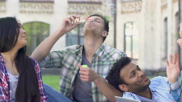 Multi-Ethnic Group of Friends Relaxing Near College and Blowing Bubbles, Slow-Mo