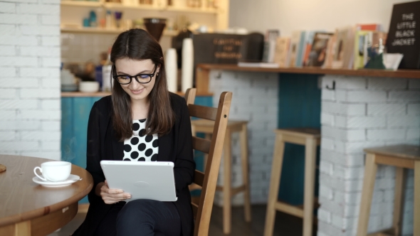 Woman Sits At a Table At a Restaurant. Carried a Tablet With Access To Internet