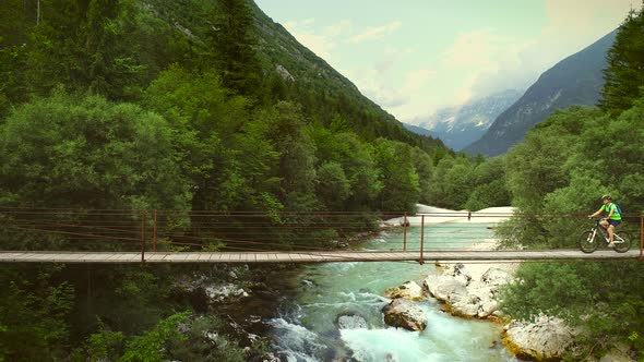 Aerial view of a woman crossing a wooden bridge on a mountain bicycle.