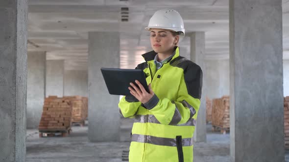 Engineer in Helmets with Tablet Device and Big Paper Drawings Discussing