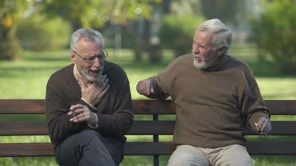 Elderly Male Coughing While Smoking Cigar, Friends Enjoying Park Rest Together