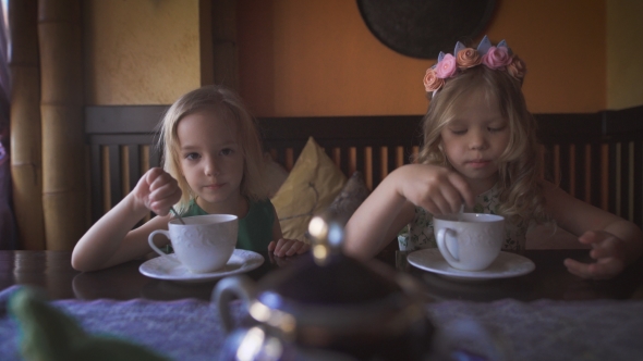 Two Cute Little Girls Are Having Tea In a Cozy Cafe