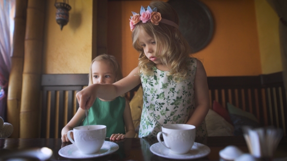 Two Pretty Little Girls Are Having Tea In a Cafe